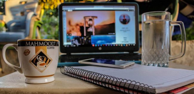 there have a laptop and cup, book, phone on a table